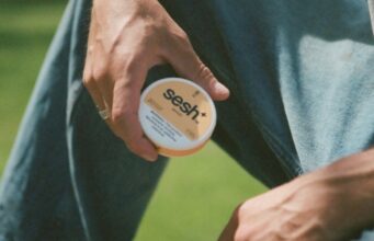 Man holding a SESH+™ mango nicotine pouch can.