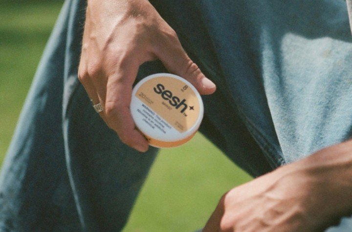 Man holding a SESH+™ mango nicotine pouch can.